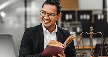 Smiling law professional sitting in an office with an open book