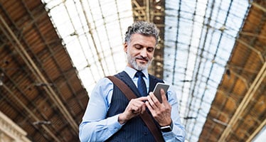 Mature law professional with smartphone in a train station