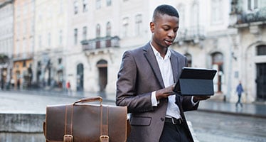Young finance and banking professional wearing a suit using tablet outdoors